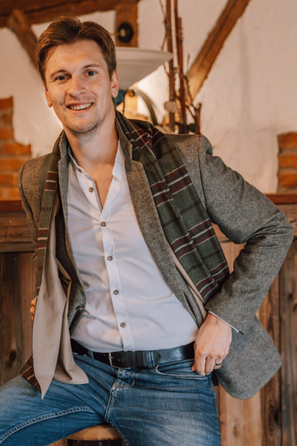 Mann trägt den karierten Lodenschal HANS lässig zu Sakko, Hemd und Jeans.