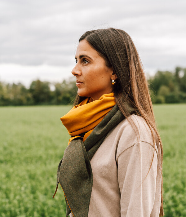 Frau trägt das Dreieckstuch PAULA aus Loden in Grün und Baumwolle in Senfgelb – nachhaltiger Lodenschal aus regionaler Merinowolle, langlebig und vielseitig kombinierbar.
